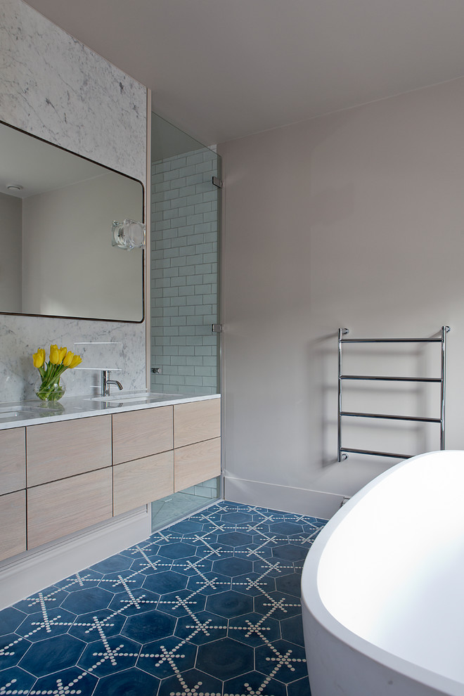 На фото: главная ванная комната в современном стиле с врезной раковиной, плоскими фасадами, светлыми деревянными фасадами, отдельно стоящей ванной, синей плиткой, белыми стенами, синим полом и белой столешницей с