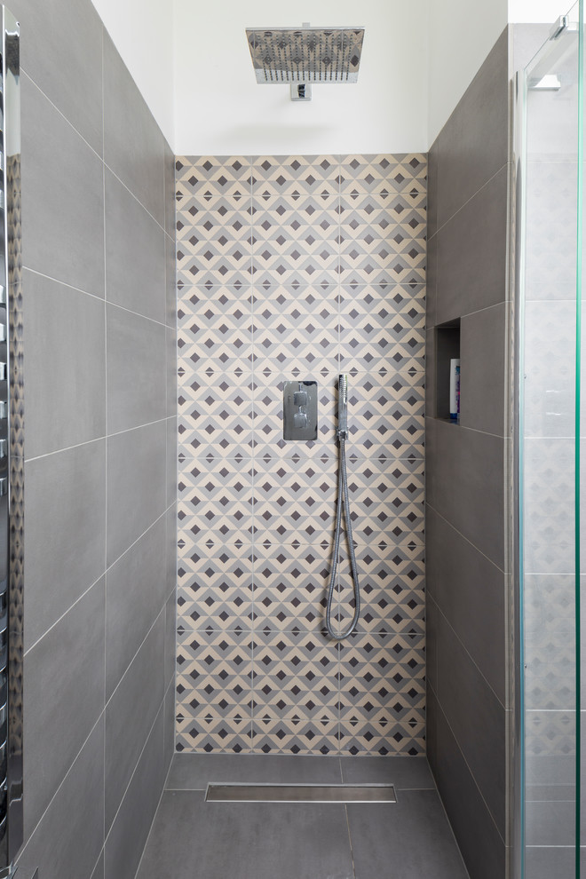 Foto på ett mellanstort funkis badrum med dusch, med släta luckor, grå skåp, en öppen dusch, en vägghängd toalettstol, grå kakel, porslinskakel, vita väggar, klinkergolv i porslin, ett integrerad handfat, grått golv och dusch med gångjärnsdörr