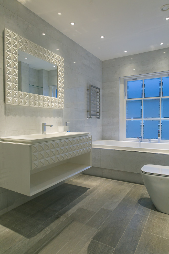 This is an example of a medium sized contemporary ensuite bathroom in London with engineered stone worktops, a built-in bath, grey tiles, porcelain tiles, white walls and porcelain flooring.