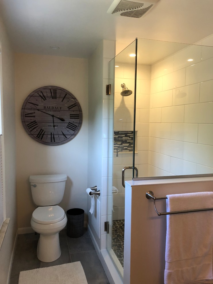 This is an example of a medium sized contemporary ensuite bathroom in Cleveland with shaker cabinets, grey cabinets, an alcove shower, a two-piece toilet, white tiles, ceramic tiles, white walls, porcelain flooring, a submerged sink, marble worktops, grey floors, a hinged door and white worktops.