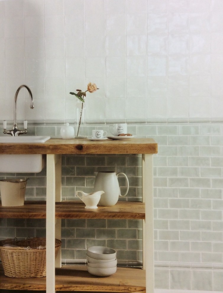 Example of a mid-sized farmhouse green tile, white tile and ceramic tile bathroom design in Burlington with open cabinets, medium tone wood cabinets, white walls, a drop-in sink and wood countertops