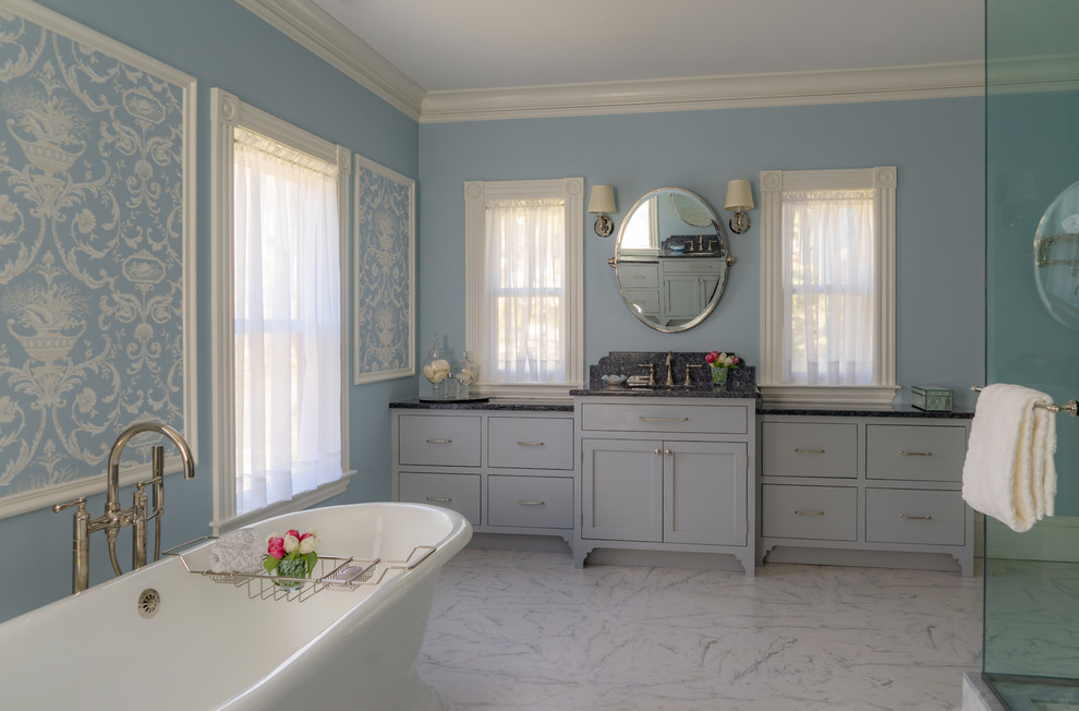 Mid-sized ornate master marble tile marble floor and white floor freestanding bathtub photo in Boston with recessed-panel cabinets, gray cabinets, a one-piece toilet and blue walls