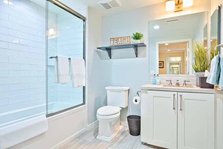 Small beach style gray tile and stone tile tub/shower combo photo in San Diego with a two-piece toilet, beige walls, an undermount sink and quartz countertops