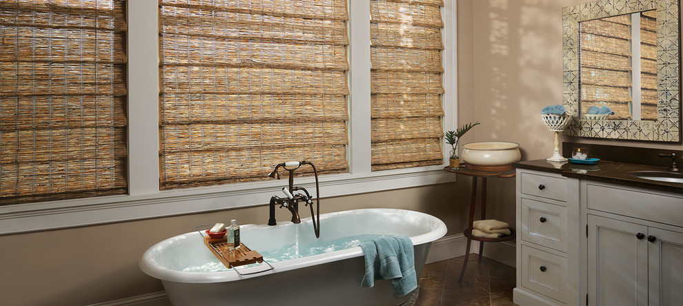 Bild på ett mellanstort eklektiskt en-suite badrum, med luckor med infälld panel, vita skåp, ett fristående badkar, beige väggar, laminatgolv, ett undermonterad handfat, bänkskiva i akrylsten och brunt golv