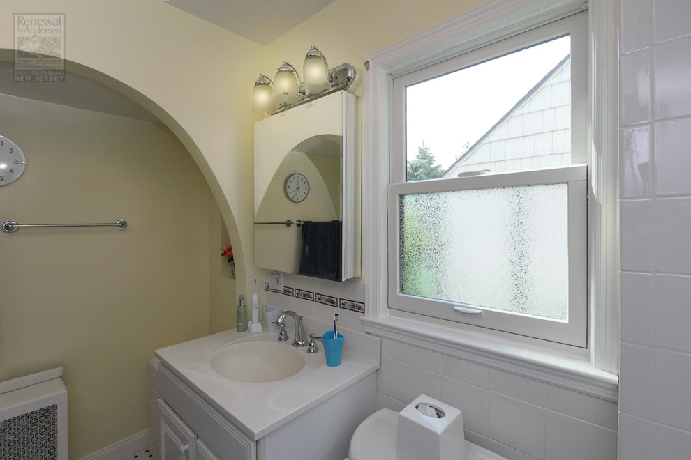 На фото: ванная комната среднего размера с белыми фасадами, белой плиткой, керамической плиткой, желтыми стенами, столешницей из искусственного кварца и белой столешницей