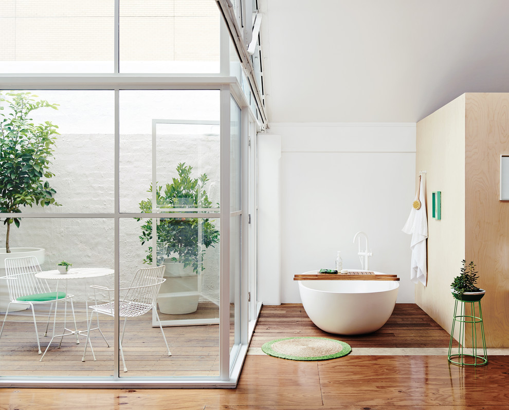 Großes Modernes Badezimmer mit weißen Schränken, freistehender Badewanne, weißer Wandfarbe und dunklem Holzboden in Melbourne
