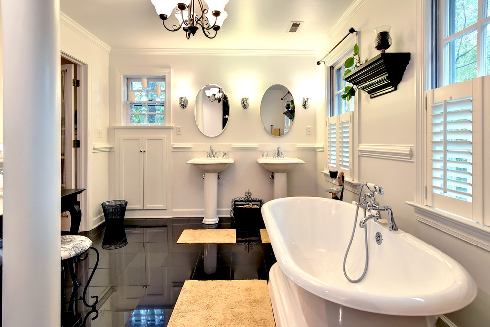 Klassisches Badezimmer mit Sockelwaschbecken, freistehender Badewanne, weißer Wandfarbe und schwarzem Boden in Sonstige