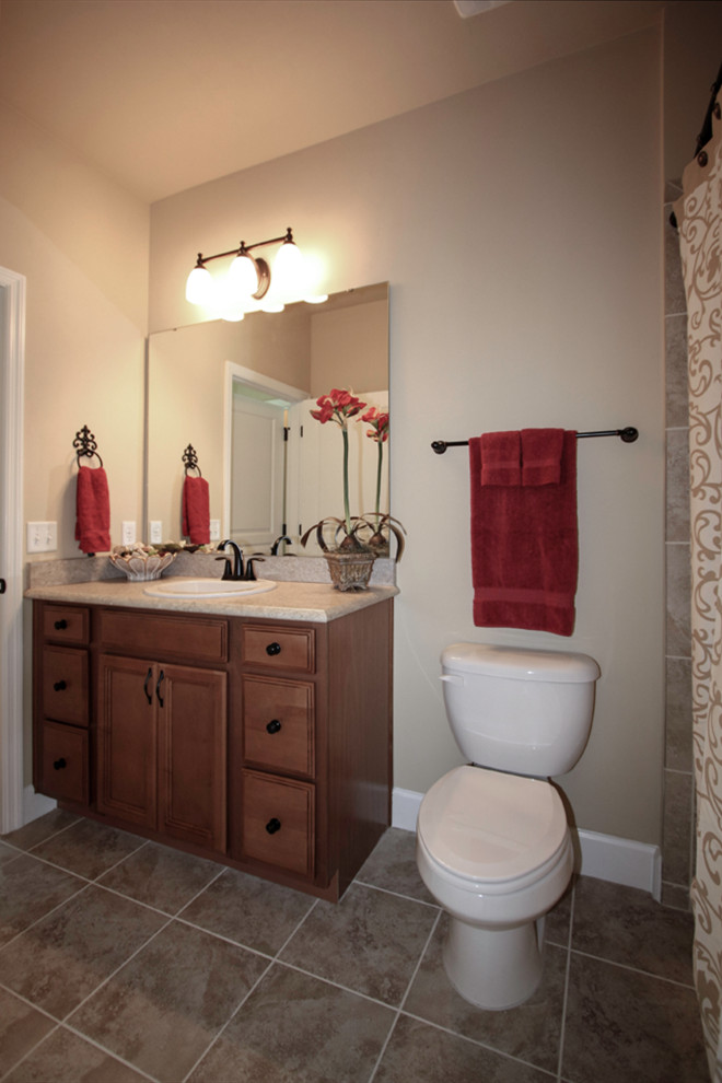 This is an example of a medium sized traditional family bathroom with shaker cabinets, medium wood cabinets, an alcove bath, a one-piece toilet, beige tiles, ceramic tiles, beige walls, porcelain flooring, a built-in sink, granite worktops, beige floors and beige worktops.