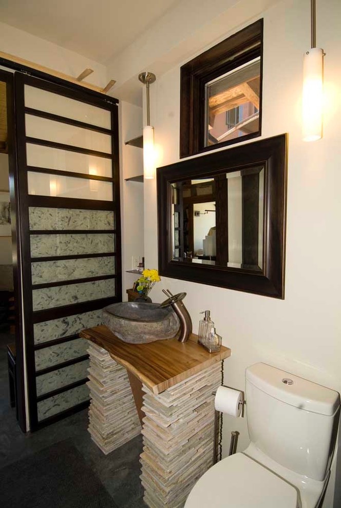 Diseño de cuarto de baño asiático pequeño con lavabo sobreencimera, armarios abiertos, puertas de armario de madera en tonos medios, encimera de madera, ducha empotrada, sanitario de dos piezas, paredes beige, suelo de cemento y aseo y ducha