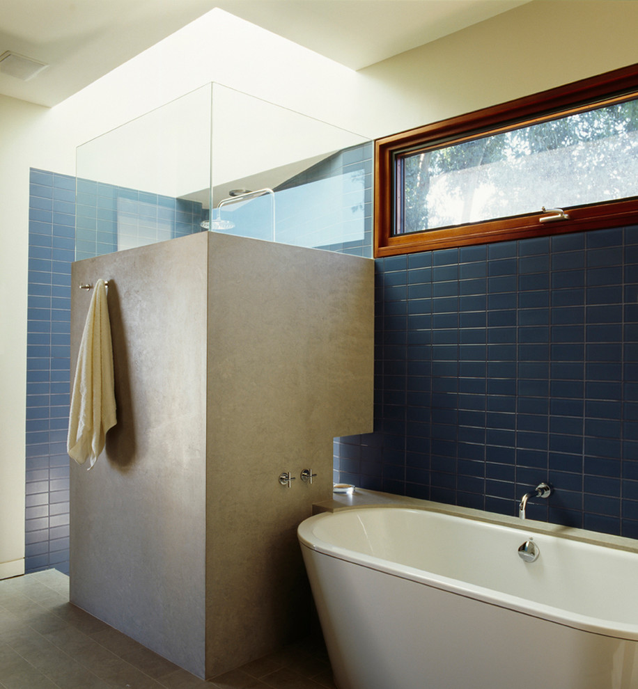 Inredning av ett modernt badrum, med ett fristående badkar, en öppen dusch, blå kakel, tunnelbanekakel och med dusch som är öppen