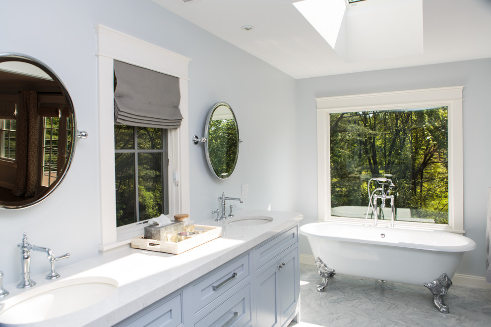 Transitional master stone tile marble floor claw-foot bathtub photo in Boston with beaded inset cabinets, blue cabinets, quartz countertops, blue walls and an undermount sink