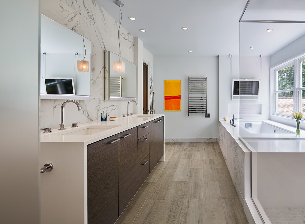 Cette image montre une salle de bain principale design en bois foncé avec un placard à porte plane, un plan de toilette en quartz modifié, un mur blanc, un lavabo encastré, une baignoire encastrée et un sol en bois brun.
