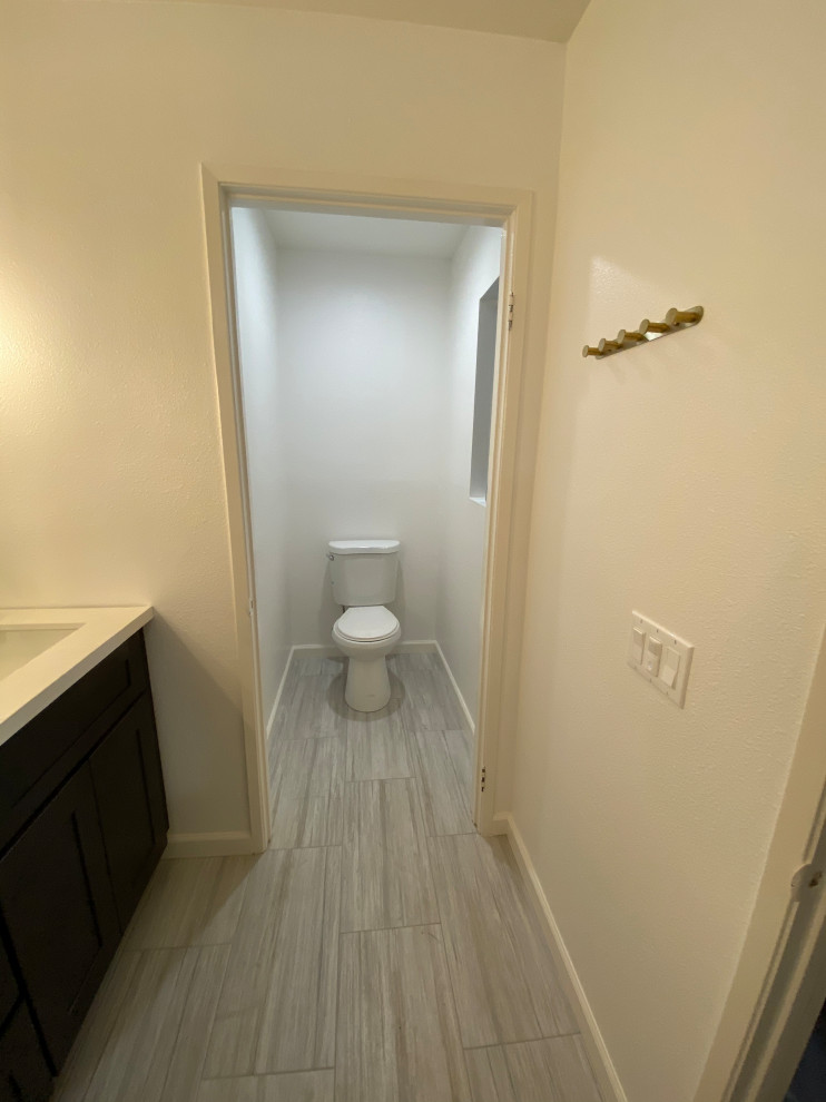 Idées déco pour une douche en alcôve principale classique en bois foncé de taille moyenne avec un placard à porte shaker, WC à poser, un carrelage jaune, des carreaux de porcelaine, un mur beige, un sol en carrelage de porcelaine, un lavabo encastré, un plan de toilette en quartz modifié, un sol gris, une cabine de douche à porte battante et un plan de toilette blanc.