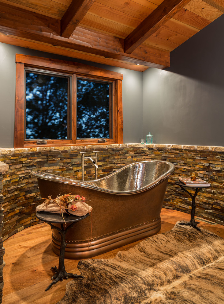 Immagine di una stanza da bagno padronale rustica con vasca freestanding, doccia ad angolo, piastrelle in pietra, pareti blu, parquet chiaro e lavabo da incasso