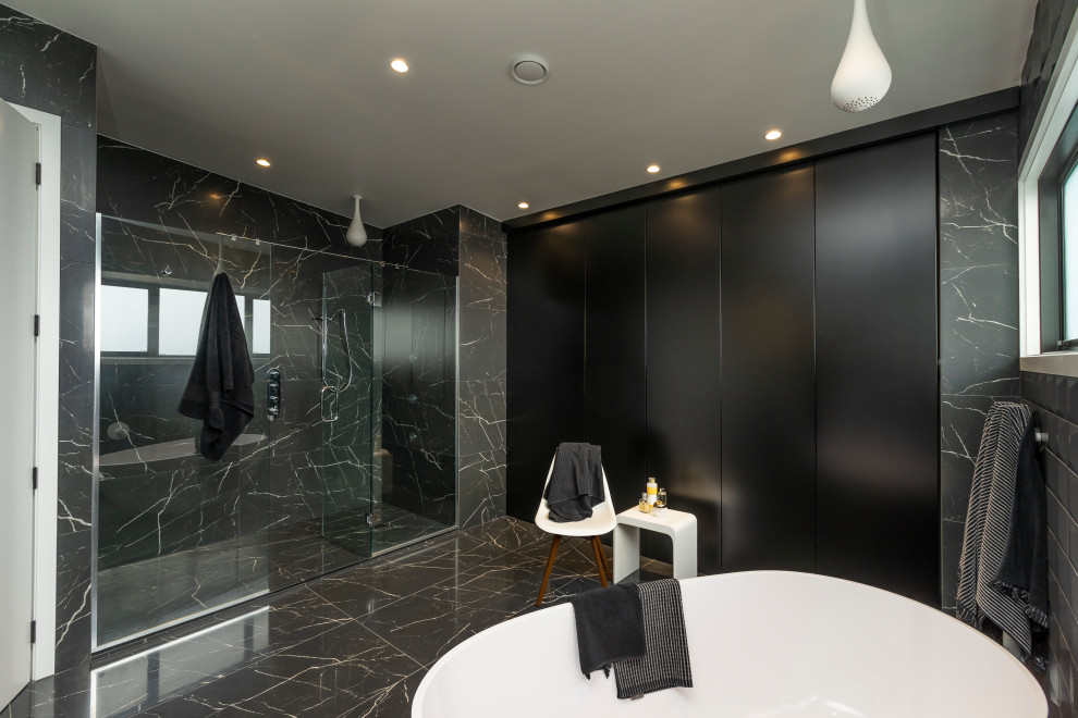 На фото: главная ванная комната среднего размера в стиле модернизм с плоскими фасадами, черными фасадами, отдельно стоящей ванной, двойным душем, инсталляцией, черной плиткой, мраморной плиткой, черными стенами, мраморным полом, врезной раковиной, столешницей из искусственного камня, черным полом, душем с распашными дверями, белой столешницей, тумбой под две раковины и подвесной тумбой