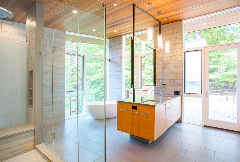 Exempel på ett stort modernt en-suite badrum, med släta luckor, skåp i mellenmörkt trä, ett fristående badkar, en dusch i en alkov, grå kakel, porslinskakel, grå väggar, klinkergolv i porslin, ett undermonterad handfat, bänkskiva i akrylsten, grått golv och med dusch som är öppen