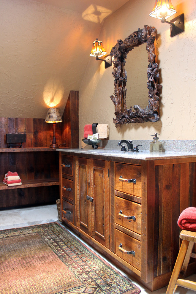 Diseño de cuarto de baño principal rústico con armarios tipo mueble, puertas de armario con efecto envejecido, lavabo bajoencimera, paredes beige y suelo de pizarra