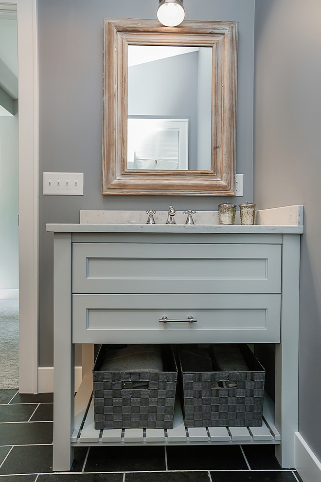 Klassisk inredning av ett badrum, med luckor med infälld panel, grå skåp, en hörndusch, en toalettstol med hel cisternkåpa, grå kakel, grå väggar, skiffergolv, ett nedsänkt handfat och marmorbänkskiva