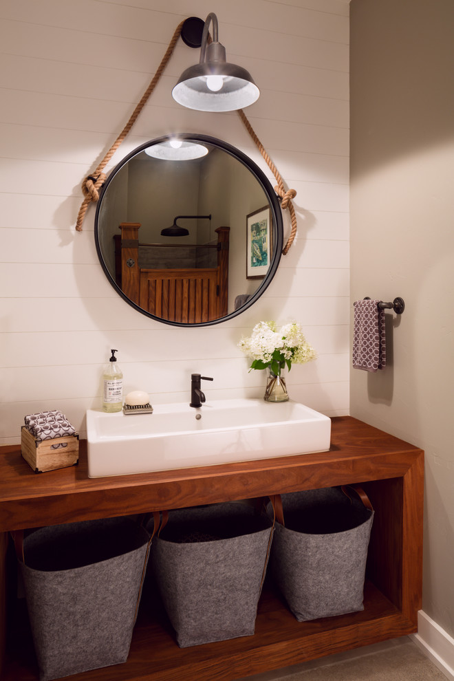Modelo de cuarto de baño campestre con armarios abiertos, puertas de armario de madera en tonos medios, paredes blancas y encimera de madera