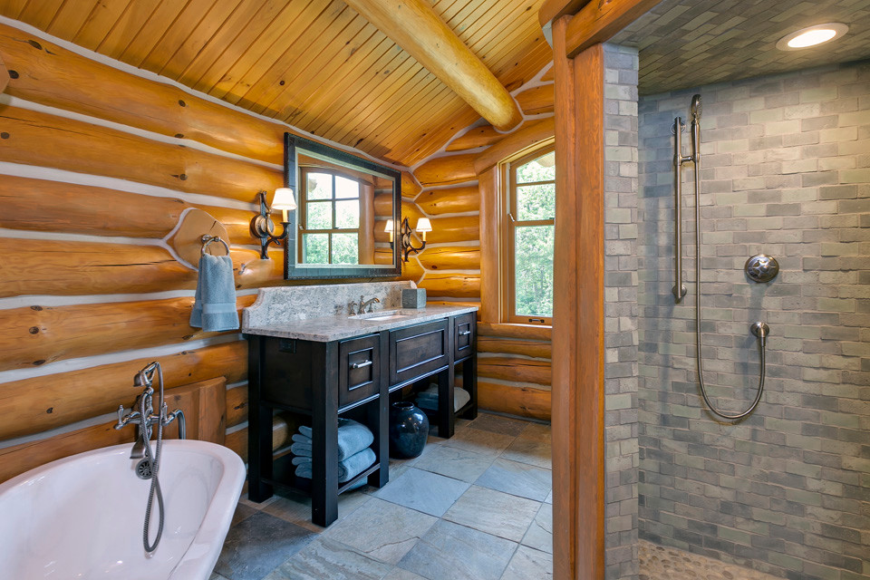 Exemple d'une grande douche en alcôve principale montagne en bois foncé avec un placard avec porte à panneau encastré, une baignoire sur pieds, un lavabo encastré et un plan de toilette en granite.