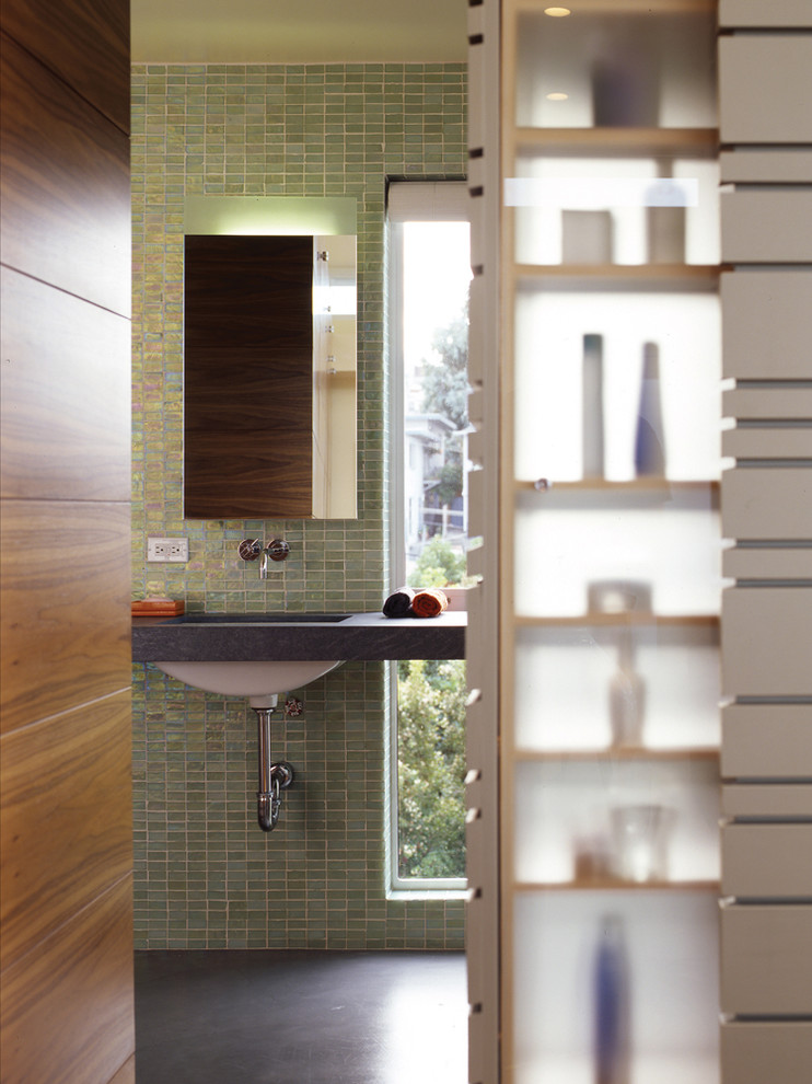 Cette image montre une salle de bain principale minimaliste de taille moyenne avec un carrelage vert, un mur vert, sol en béton ciré, un lavabo encastré et un plan de toilette en calcaire.