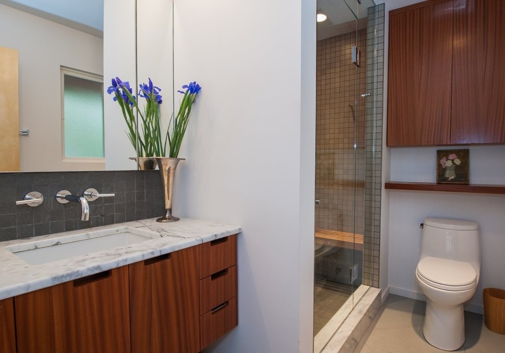 Réalisation d'une petite salle de bain minimaliste en bois brun avec un placard à porte plane, un carrelage noir, un carrelage de pierre, un mur blanc, un sol en carrelage de porcelaine, un lavabo encastré et un plan de toilette en marbre.