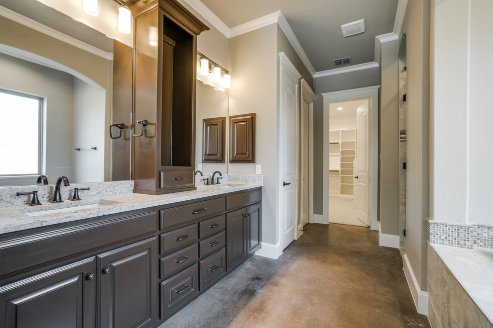 Medium sized classic ensuite bathroom in Dallas with raised-panel cabinets, brown cabinets, a built-in bath, a built-in shower, a two-piece toilet, beige tiles, porcelain tiles, beige walls, concrete flooring, a submerged sink and granite worktops.