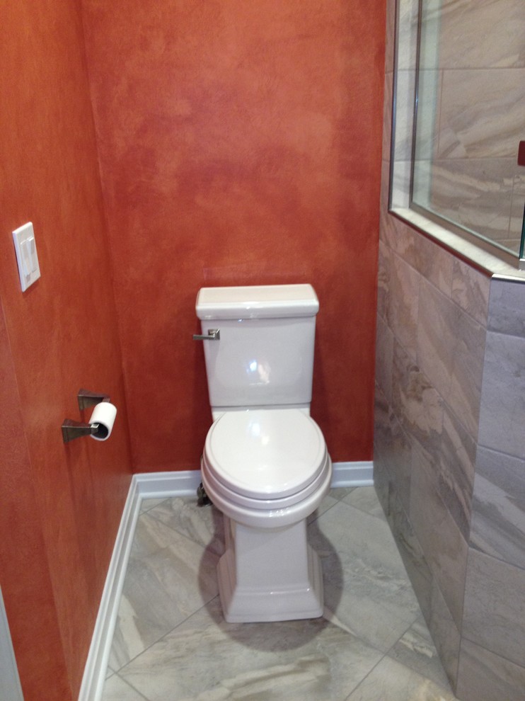 Idée de décoration pour un WC et toilettes tradition de taille moyenne avec un lavabo encastré, un placard avec porte à panneau surélevé, des portes de placard blanches, un plan de toilette en granite, un carrelage gris, des carreaux de porcelaine, un mur orange et un sol en carrelage de porcelaine.