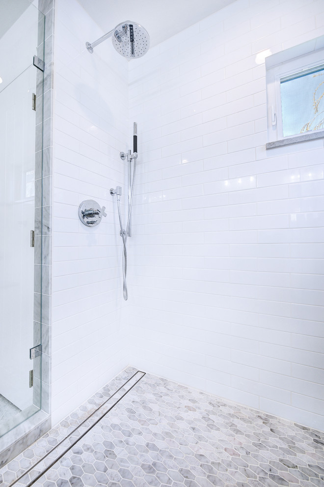На фото: главная ванная комната среднего размера в стиле неоклассика (современная классика) с белыми фасадами, белой плиткой, мраморным полом, душем с распашными дверями, фасадами с утопленной филенкой, угловым душем, унитазом-моноблоком, мраморной плиткой, белыми стенами, врезной раковиной, столешницей из известняка, белым полом и серой столешницей