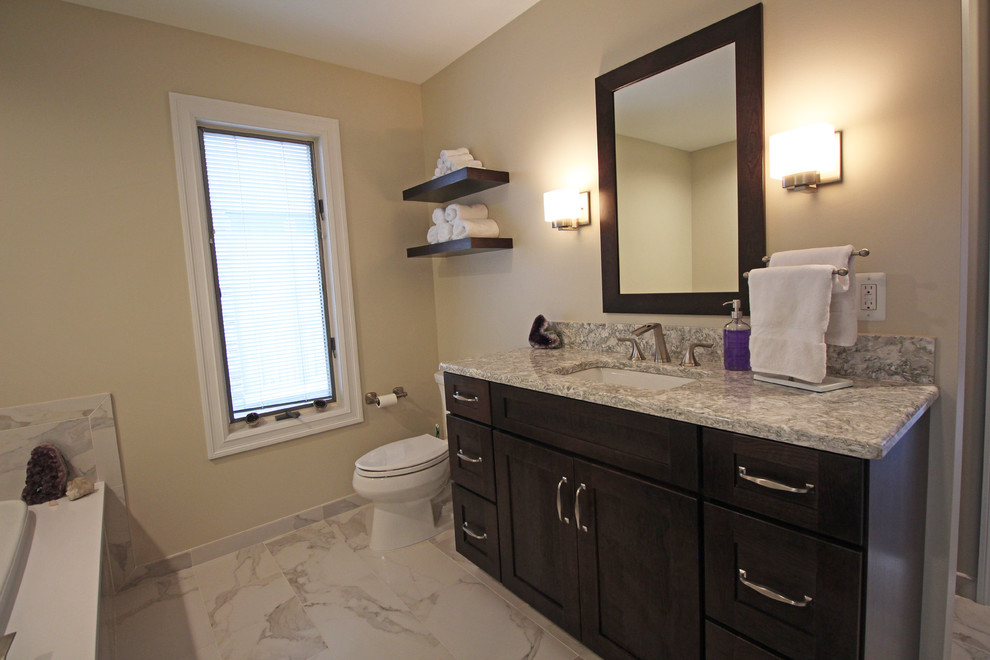 Photo of a large classic ensuite bathroom in Detroit with shaker cabinets, dark wood cabinets, a built-in bath, a corner shower, a two-piece toilet, white tiles, porcelain tiles, beige walls, porcelain flooring, a submerged sink, engineered stone worktops, white floors, a hinged door and multi-coloured worktops.