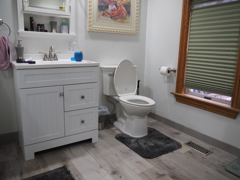 Foto på ett mellanstort vintage badrum med dusch, med skåp i shakerstil, vita skåp, en hörndusch, en toalettstol med separat cisternkåpa, grå kakel, keramikplattor, grå väggar, laminatgolv, ett undermonterad handfat, bänkskiva i kvarts, grått golv och med dusch som är öppen