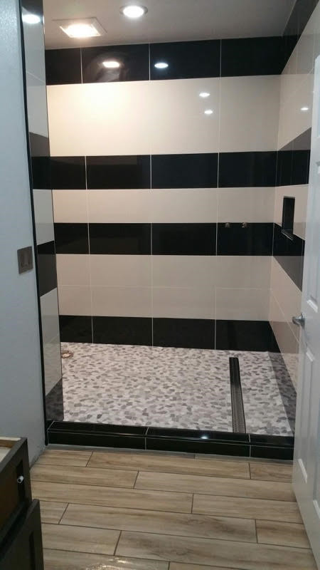 Exemple d'une douche en alcôve moderne avec un carrelage noir et blanc, des carreaux de céramique et un sol marron.