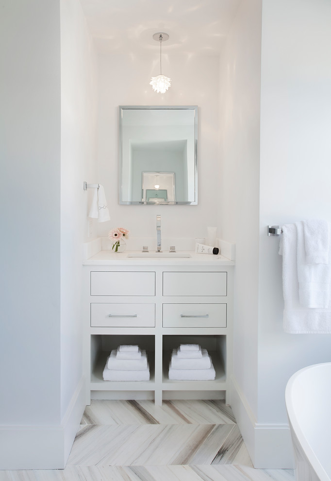 Cette image montre une salle de bain traditionnelle avec un placard à porte plane, des portes de placard blanches, un mur blanc et un lavabo encastré.