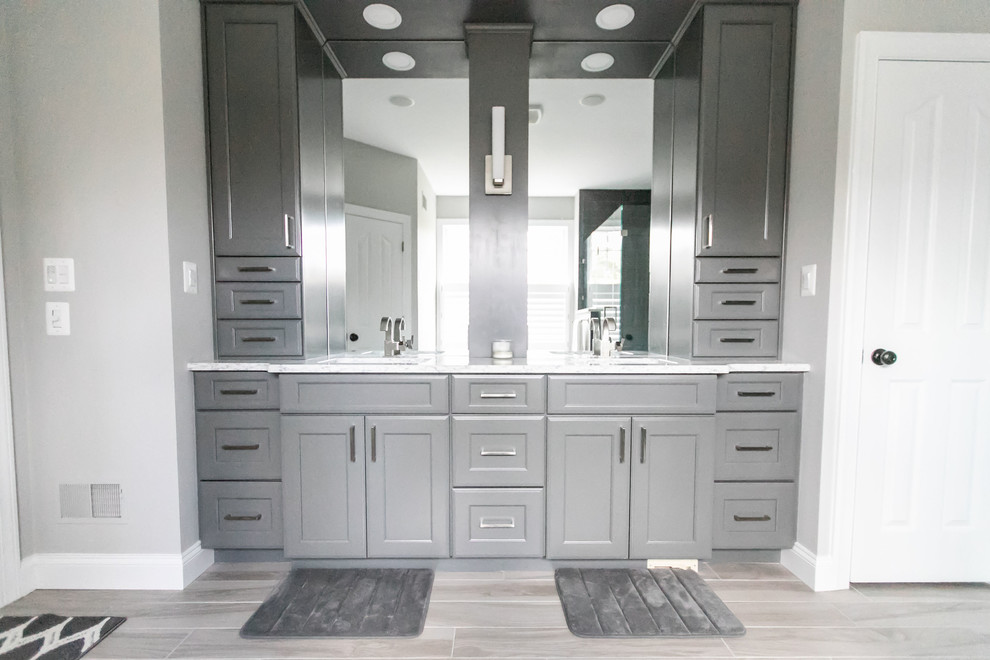 This is an example of a medium sized contemporary ensuite bathroom in Baltimore with flat-panel cabinets, grey cabinets, a freestanding bath, a corner shower, grey tiles, porcelain tiles, grey walls, porcelain flooring, a submerged sink, engineered stone worktops, grey floors, a hinged door and white worktops.