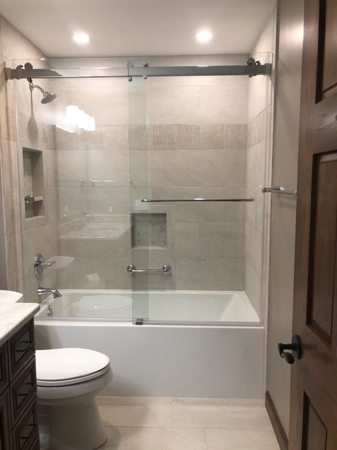 This is an example of a large classic bathroom in Indianapolis with brown cabinets, a built-in bath, beige tiles, slate tiles, beige walls, porcelain flooring, a submerged sink, quartz worktops, beige floors, a sliding door, white worktops, beaded cabinets, a shower/bath combination and a two-piece toilet.