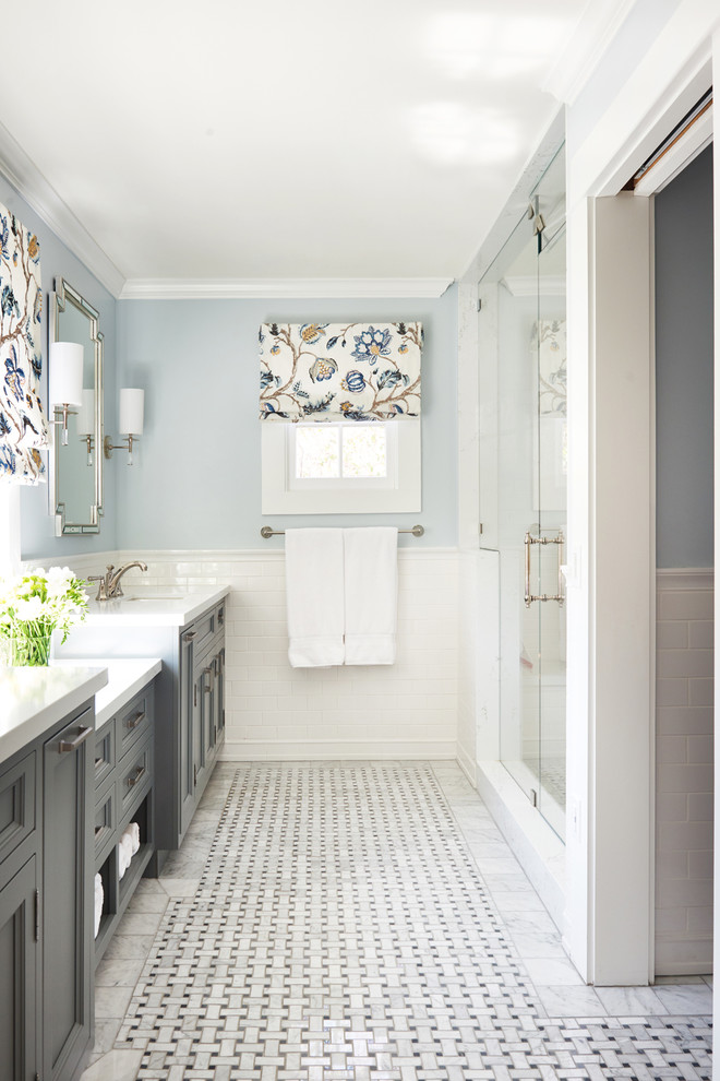 Cette image montre une douche en alcôve traditionnelle avec un placard avec porte à panneau encastré, des portes de placard grises, un mur bleu, un sol en marbre, un lavabo encastré, un sol multicolore, une cabine de douche à porte battante et un plan de toilette blanc.