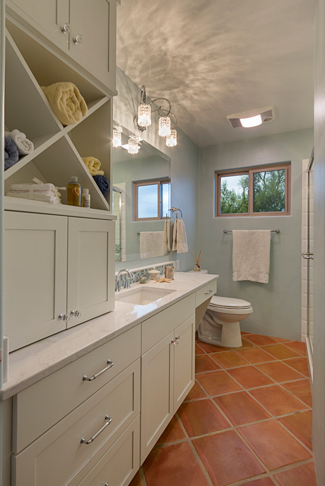 Inspiration for a mid-sized timeless master terra-cotta tile corner shower remodel in Orange County with recessed-panel cabinets, white cabinets, a two-piece toilet, blue walls and an undermount sink