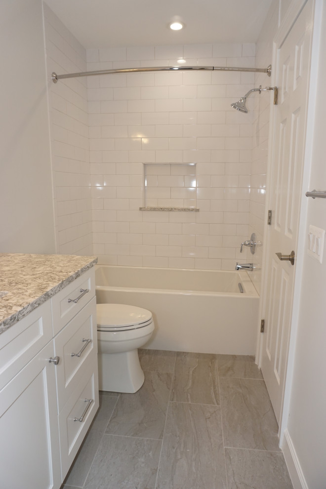 This is an example of a medium sized traditional family bathroom in DC Metro with recessed-panel cabinets, white cabinets, an alcove bath, a shower/bath combination, a two-piece toilet, white tiles, ceramic tiles, white walls, ceramic flooring, a submerged sink, engineered stone worktops, grey floors, a shower curtain and multi-coloured worktops.