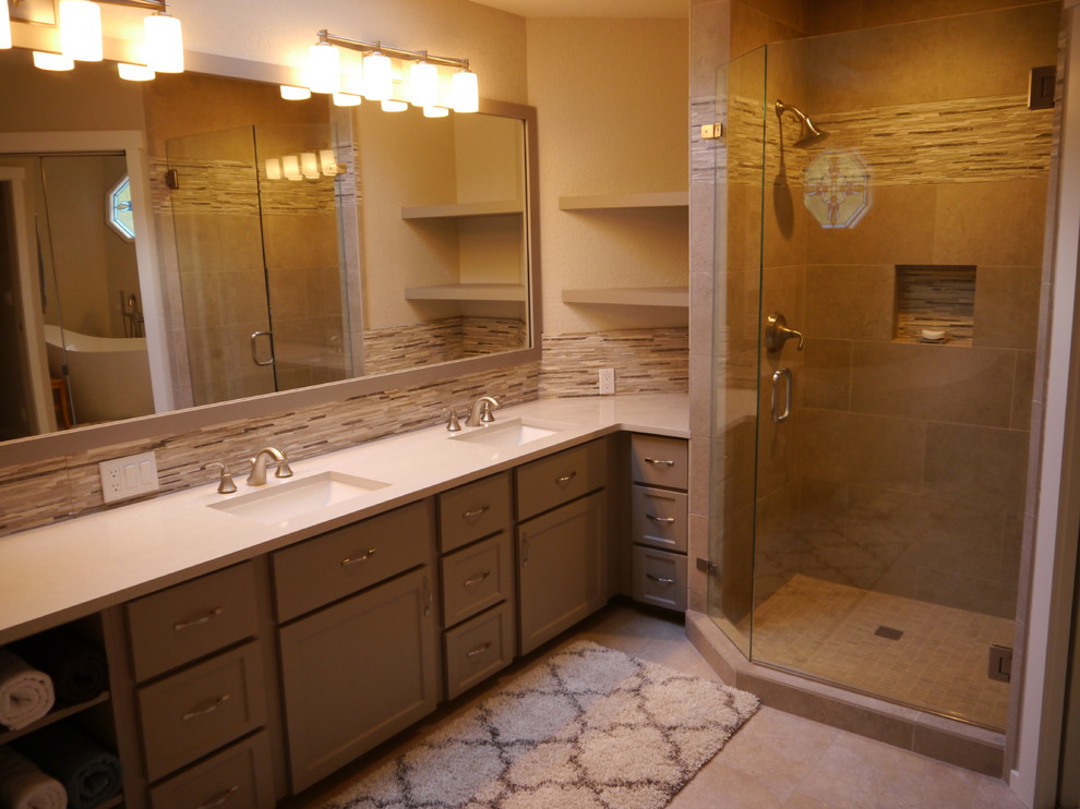 This is an example of a large traditional ensuite bathroom in Seattle with shaker cabinets, grey cabinets, a freestanding bath, a two-piece toilet, beige tiles, porcelain tiles, beige walls, vinyl flooring, a submerged sink, solid surface worktops, a hinged door and beige worktops.