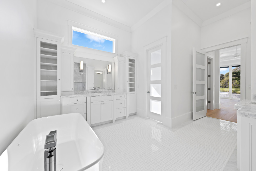 Klassisk inredning av ett mycket stort en-suite badrum, med luckor med infälld panel, vita skåp, ett fristående badkar, en dusch i en alkov, vita väggar, klinkergolv i keramik, ett undermonterad handfat, vitt golv och med dusch som är öppen