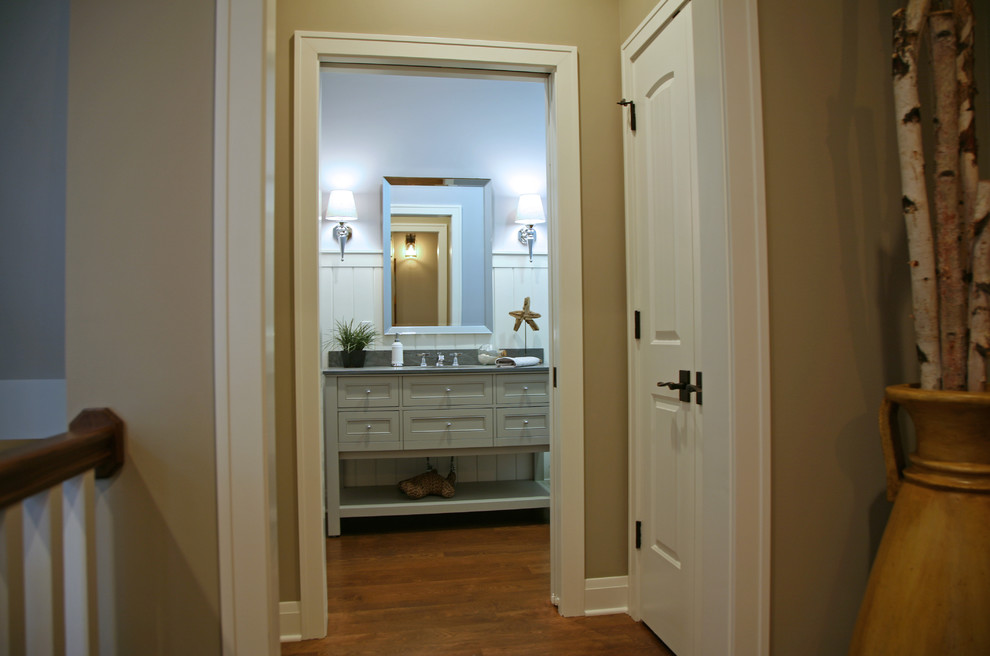 Klassisk inredning av ett mellanstort grå grått badrum, med ett undermonterad handfat, luckor med infälld panel, grå skåp, bänkskiva i täljsten, en toalettstol med hel cisternkåpa, grå kakel, blå väggar och ljust trägolv