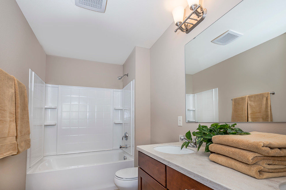 Foto på ett mellanstort funkis badrum, med skåp i mellenmörkt trä, en dusch/badkar-kombination och beige väggar