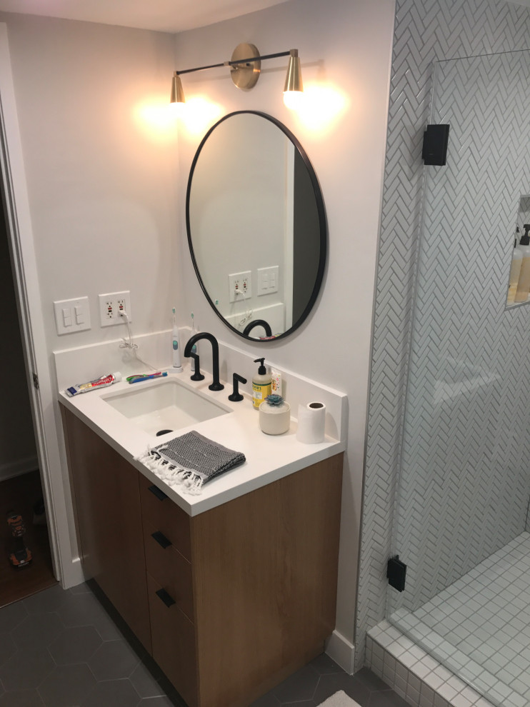 Photo of a shower room bathroom in Los Angeles with flat-panel cabinets, brown cabinets, a one-piece toilet, white tiles, metal tiles, white walls, porcelain flooring, a built-in sink, engineered stone worktops, grey floors, a hinged door and white worktops.
