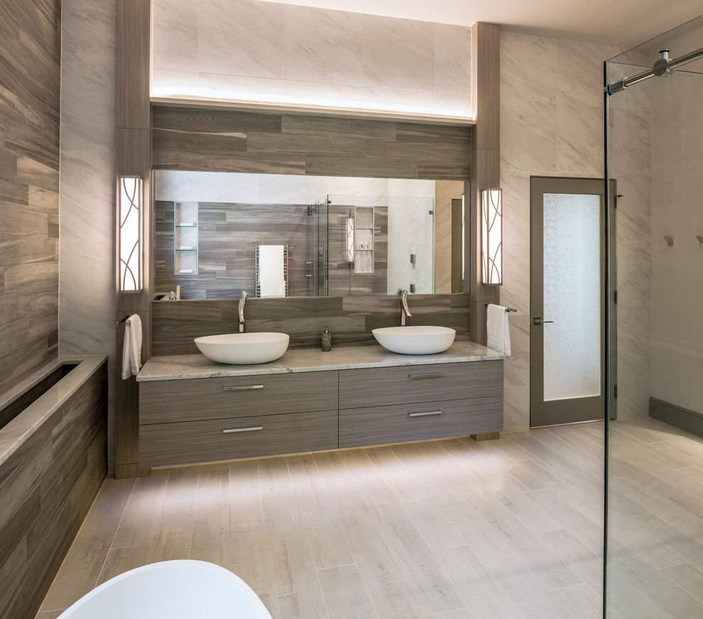 На фото: большая главная ванная комната в стиле неоклассика (современная классика) с плоскими фасадами, серыми фасадами, отдельно стоящей ванной, угловым душем, биде, серой плиткой, серыми стенами, настольной раковиной, серым полом и душем с раздвижными дверями с