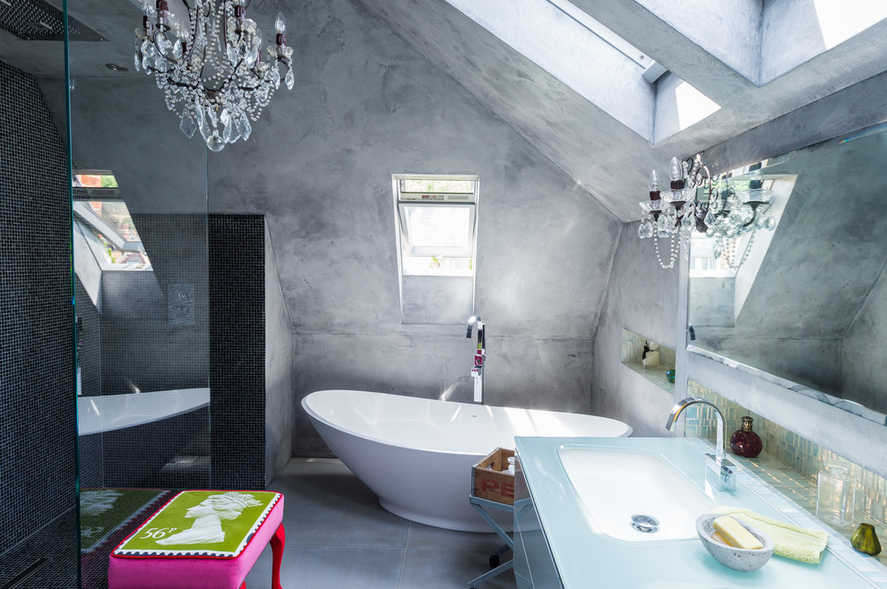 Idée de décoration pour une salle de bain principale bohème avec un lavabo encastré, un plan de toilette en verre, une baignoire indépendante, une douche ouverte, un carrelage noir, mosaïque, un mur gris, sol en béton ciré et aucune cabine.
