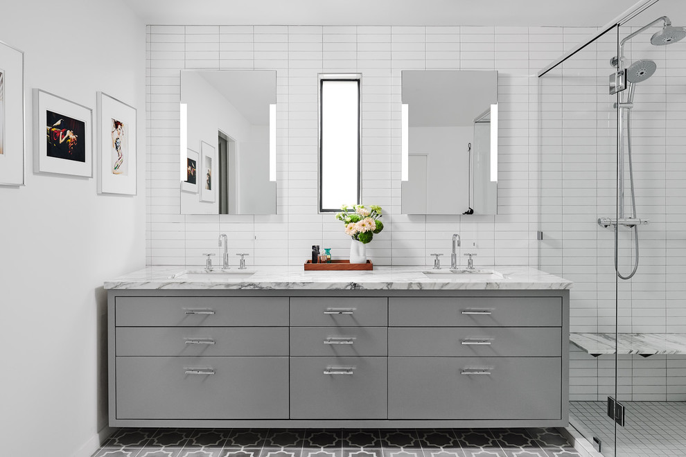Идея дизайна: главная ванная комната среднего размера в современном стиле с плоскими фасадами, серыми фасадами, отдельно стоящей ванной, угловым душем, унитазом-моноблоком, белой плиткой, плиткой кабанчик, белыми стенами, полом из цементной плитки, врезной раковиной, мраморной столешницей, серым полом, душем с распашными дверями и белой столешницей