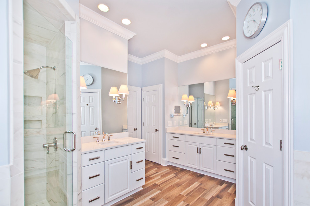Large elegant master white tile and porcelain tile medium tone wood floor and brown floor bathroom photo in Nashville with raised-panel cabinets, white cabinets, a two-piece toilet, gray walls, an undermount sink, quartz countertops, a hinged shower door and white countertops
