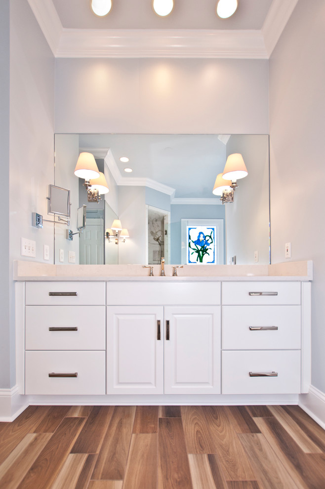 Bathroom - large traditional master white tile and porcelain tile medium tone wood floor and brown floor bathroom idea in Nashville with raised-panel cabinets, white cabinets, a two-piece toilet, gray walls, an undermount sink, quartz countertops, a hinged shower door and white countertops