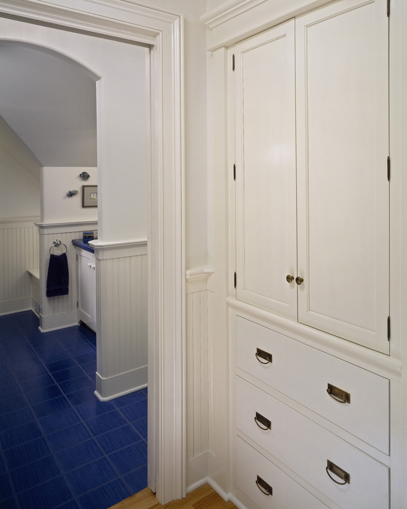 Klassisk inredning av ett badrum, med vita skåp och blått golv