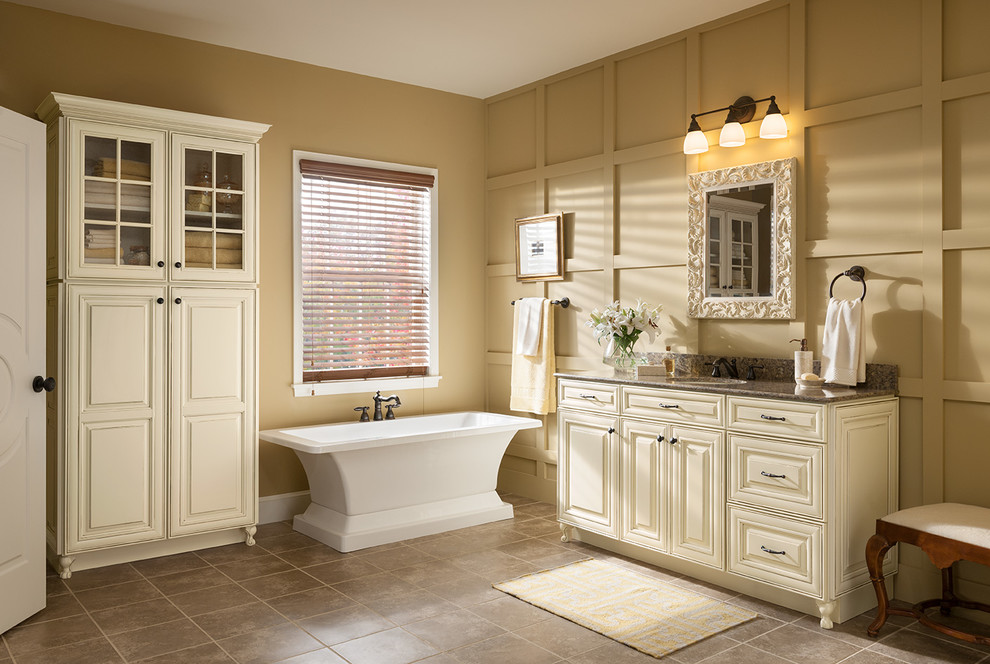 Imagen de cuarto de baño tradicional con lavabo bajoencimera, armarios con paneles con relieve, puertas de armario beige, bañera exenta, baldosas y/o azulejos beige y ventanas